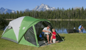 green tent by lake and mountains