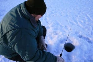 man ice fishing on lake