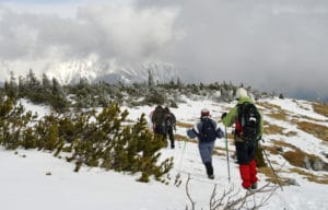 3 winter backpackers trekking thru snow