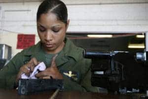 female soldier cleaning machine gun