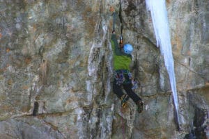 man scaling cliff face