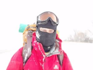 man in red coat and balaclava during snowstorm