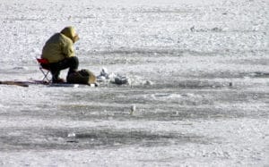 angler ice fishing on lake