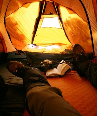 gaitered feet in winter tent with camera and book