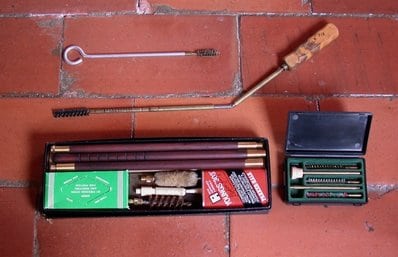 old gun cleaning kit on brick