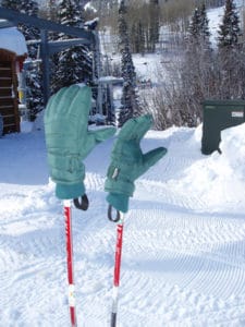 Two gloves on ski poles winter background