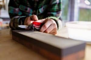 man sharpening pocket knife on sharpening stone