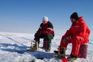 two ice anglers around hole