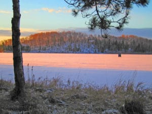 ice fishing shack on ice during sunset