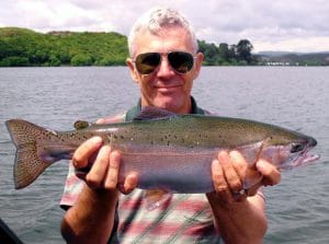 angler holding lake trout on lake